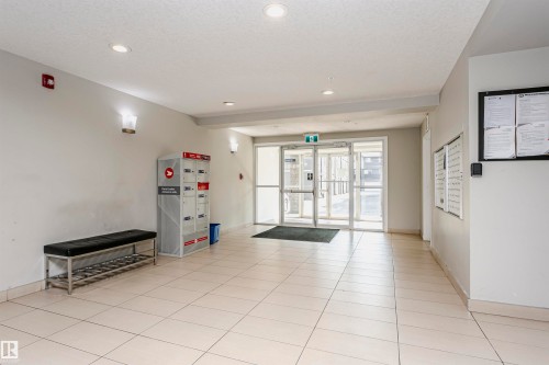 Entrance hallway featuring light-colored tile flooring, overhead recessed lighting, and wall-mounted sconces - #104 9519 160 Av Nw, Edmonton, AB - Indoor Photo Showing Other Room