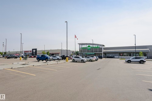Expansive paved parking lot featuring marked spaces and multiple light poles - #104 9519 160 Av Nw, Edmonton, AB - Outdoor