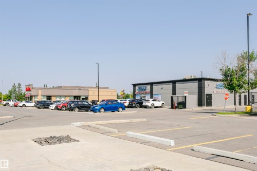 Commercial building featuring a grey facade with black trim and a prominent storefront sign - #104 9519 160 Av Nw, Edmonton, AB - Outdoor