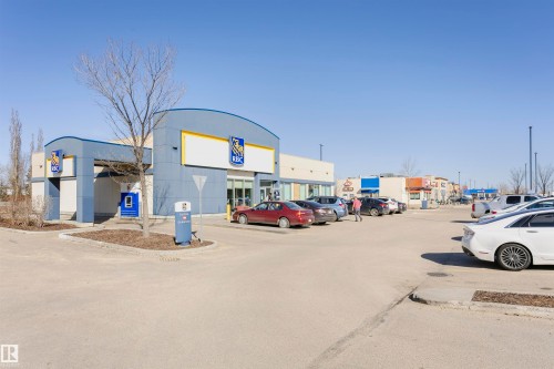 Modern commercial building featuring a curved facade, prominent signage, and a dedicated drive-through area - #104 9519 160 Av Nw, Edmonton, AB - Outdoor