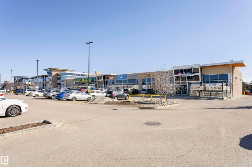 Retail complex featuring expansive storefront windows, integrated signage, and a large paved parking lot - #104 9519 160 Av Nw, Edmonton, AB - Outdoor