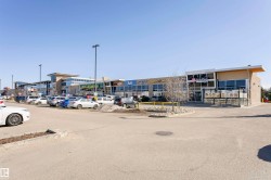 Retail complex featuring expansive storefront windows, integrated signage, and a large paved parking lot - 