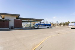 Modern transit facility featuring a large concrete parking area, extensive glass curtain walls, a flat roofline, and integrated brick accents - 