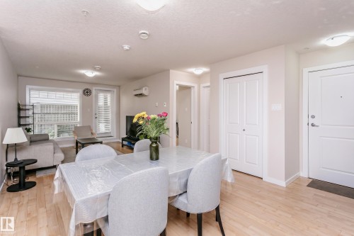 Open-concept living and dining area with wood-finish flooring - #104 9519 160 Av Nw, Edmonton, AB - Indoor