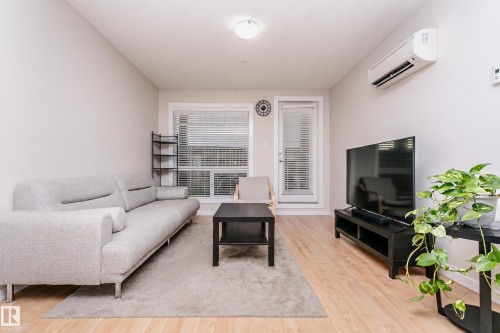 Bright living area with wood-finish flooring and a light neutral color palette - #104 9519 160 Av Nw, Edmonton, AB - Indoor Photo Showing Living Room