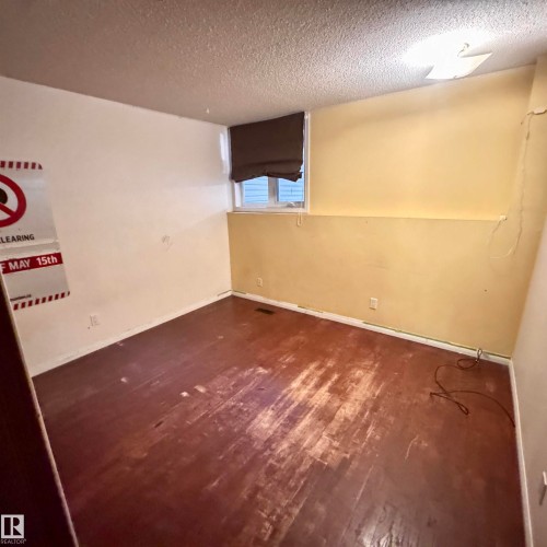 Spacious room featuring distressed wood-finish flooring, a window with a brown roll-down shade, and dual-tone wall paint - 4821 11A Avenue Nw, Edmonton, AB - Indoor Photo Showing Other Room