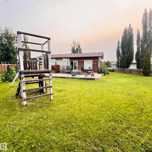 Expansive level grounds featuring a manicured lawn with mature poplar trees and evergreen landscaping - 4821 11A Avenue Nw, Edmonton, AB - Outdoor With Deck Patio Veranda