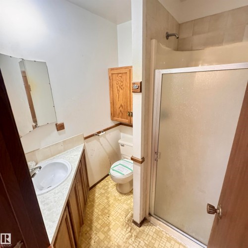 Functional bathroom layout featuring a pedestal sink with marble-finish countertop, ceramic tile flooring in a neutral mosaic pattern, and a separate shower enclosure with glass door - 4821 11A Avenue Nw, Edmonton, AB - Indoor Photo Showing Bathroom