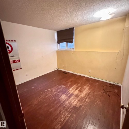Finished basement room featuring wood-finish flooring, fresh yellow wall paint, and recessed ceiling lighting - 4821 11A Avenue Nw, Edmonton, AB - Indoor Photo Showing Other Room