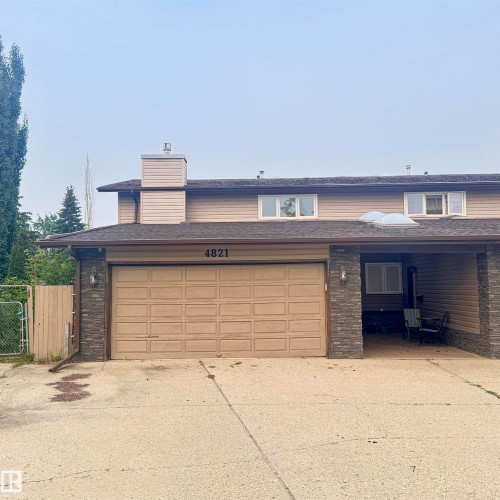 Welcoming front elevation featuring a brick and siding exterior with a tan garage door, covered carport area, and mature landscaping - 4821 11A Avenue Nw, Edmonton, AB - Outdoor