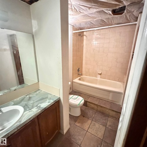 Full bathroom featuring ceramic tile flooring, an alcove bathtub with tile surround and shower enclosure, pedestal sink with mirror, and toilet - 4821 11A Avenue Nw, Edmonton, AB - Indoor Photo Showing Bathroom