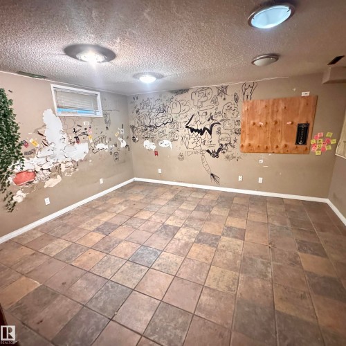Spacious basement recreation room featuring tile flooring in a mixed-tone pattern, recessed ceiling lighting, and white trim accents - 4821 11A Avenue Nw, Edmonton, AB - Indoor Photo Showing Other Room