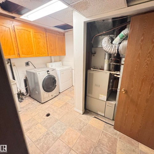 Dedicated laundry room featuring wood-finish cabinetry, tile flooring, and a front-load washer with accompanying dryer - 4821 11A Avenue Nw, Edmonton, AB - Indoor Photo Showing Laundry Room