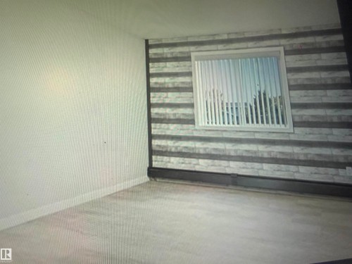 Light wood-finish flooring with crisp white baseboards - #106 592 Hooke Rd Nw, Edmonton, AB 