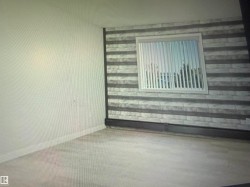 Light-toned flooring, accent wall with horizontal paneling, white window trim, and white vertical blinds  Has walk through Closet and Ensuite - 