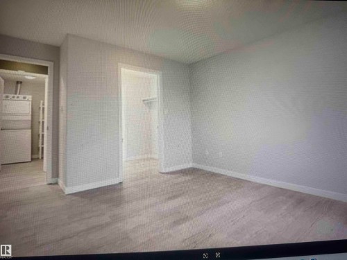 Walk Thru Closet into 4 piece Ensuite.  Bright room featuring light wood-finish flooring, white baseboards, and neutral wall tones - #106 592 Hooke Rd Nw, Edmonton, AB 
