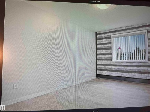 Wall-mounted light fixture, window with horizontal blinds, and a textured accent wall - #106 592 Hooke Rd Nw, Edmonton, AB 