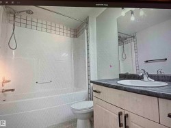 Bathroom featuring a white tub, shower with a tiled surround, toilet, vanity with a countertop, and an integrated sink with a chrome faucet - 