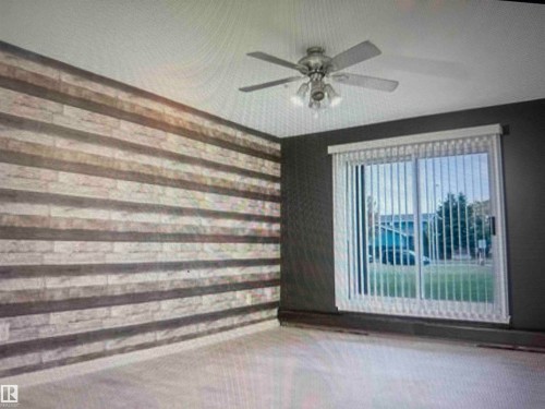 Patio Door onto large grassy area.  Gas BBQ hook-up.  Accent wall with horizontal wood-finish planks complemented by a ceiling fan with integrated lighting - #106 592 Hooke Rd Nw, Edmonton, AB 