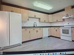 Kitchen featuring light wood-finish cabinetry with dark hardware, a white subway tile backsplash, and dark countertops - 