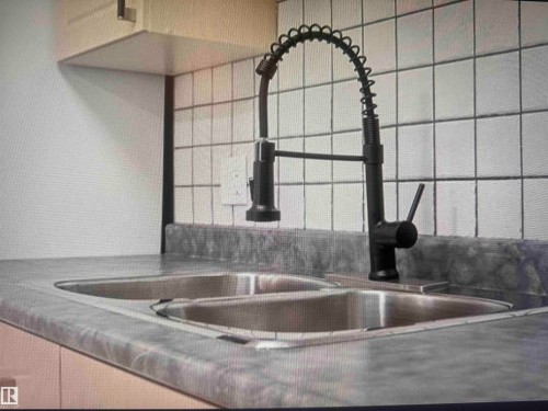 Dual basin stainless steel sink with a matte black pull-down faucet - #106 592 Hooke Rd Nw, Edmonton, AB 