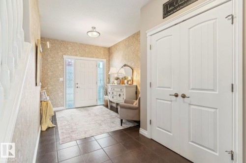 Welcoming foyer showcasing dark tile flooring, neutral patterned wallcovering, and abundant natural light from glass-paneled entry doors - 22 Voleta Crest, Spruce Grove, AB - Indoor Photo Showing Other Room