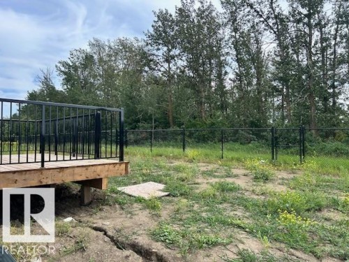 Outdoor wood-finish decking with black metal railing, overlooking a fenced yard and mature trees - 247 Edgemont Green Green Nw, Edmonton, AB 