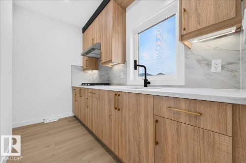 Kitchen featuring wood-finish cabinetry, white countertops, and a light-toned backsplash - 403 172 Avenue Nw, Edmonton, AB - Indoor Photo Showing Kitchen