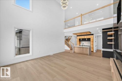 Open-concept living space featuring high ceilings, light wood-finish flooring, and a contemporary kitchen with an island - 403 172 Avenue Nw, Edmonton, AB - Indoor
