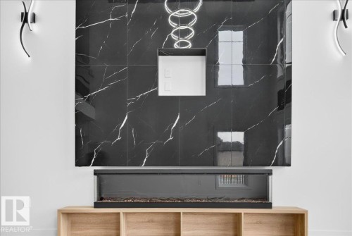 Striking feature wall with large format black marbled tiles, linear electric fireplace, built-in media niche, and recessed lighting - 403 172 Avenue Nw, Edmonton, AB - Other
