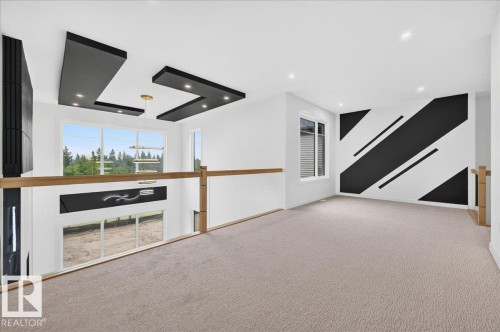 Carpeted open loft space featuring a decorative accent wall, recessed lighting, and a contemporary ceiling light fixture - 403 172 Avenue Nw, Edmonton, AB - Indoor Photo Showing Other Room