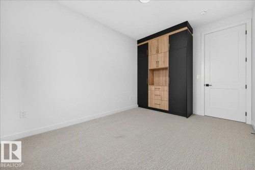 Built-in cabinetry featuring black and light wood-finish panels with gold-tone hardware - 403 172 Avenue Nw, Edmonton, AB - Indoor Photo Showing Other Room