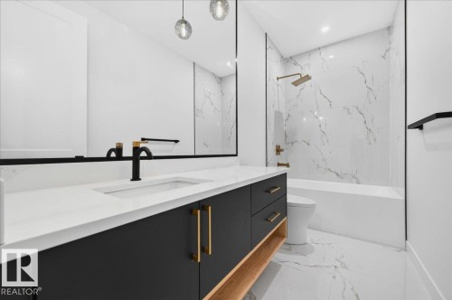 Modern bathroom vanity with a white countertop and integrated sink, featuring a matte black faucet with gold accents - 403 172 Avenue Nw, Edmonton, AB - Indoor Photo Showing Bathroom