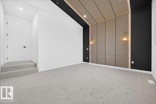Spacious interior featuring a wood-slat accent wall extending to the ceiling, two wall-mounted sconces, and recessed lighting - 403 172 Avenue Nw, Edmonton, AB - Indoor Photo Showing Other Room