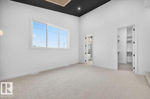 Spacious room featuring light-toned carpeting, a large multipane window, and bright white walls - 403 172 Avenue Nw, Edmonton, AB - Indoor Photo Showing Other Room