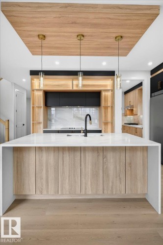 Waterfall island with a white countertop and wood-finish cabinetry - 403 172 Avenue Nw, Edmonton, AB - Indoor Photo Showing Kitchen With Upgraded Kitchen