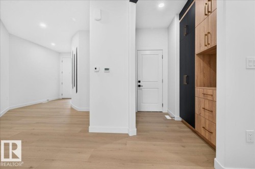 Contemporary entryway featuring light wood-finish flooring, recessed lighting, and a built-in storage unit with black and wood-tone cabinetry and gold-tone hardware - 403 172 Avenue Nw, Edmonton, AB - Indoor Photo Showing Other Room