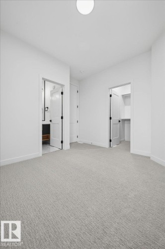 Spacious room featuring light gray textured carpeting, white walls, and a ceiling-mounted light fixture - 403 172 Avenue Nw, Edmonton, AB - Indoor Photo Showing Other Room