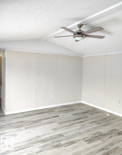 Spacious interior room featuring wood-finish flooring, light-toned wall paneling, and a contemporary ceiling fan with integrated lighting - 4819 51 Avenue, Millet, AB - Indoor Photo Showing Other Room