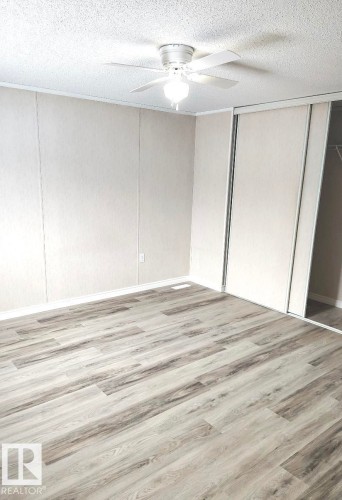 Wood-finish flooring throughout, complemented by a ceiling fan with integrated lighting - 4819 51 Avenue, Millet, AB - Indoor Photo Showing Other Room