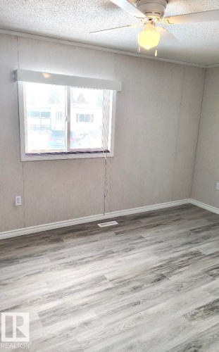 Room with wood-finish flooring, a window with a valance, and a ceiling fan with integrated lighting - 4819 51 Avenue, Millet, AB - Indoor Photo Showing Other Room