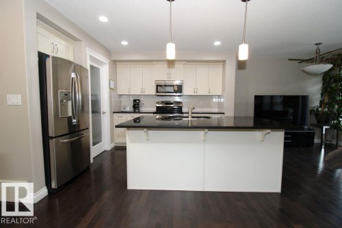 Kitchen featuring a central island with a dark countertop, white cabinetry, and stainless steel appliances - 3048 Harvey Crescent Nw, Edmonton, AB - Indoor Photo Showing Kitchen