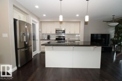 Kitchen featuring a central island with a dark countertop, white cabinetry, and stainless steel appliances - 
