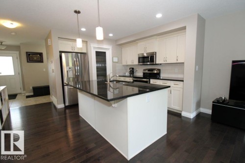 Kitchen featuring a central island with a dark countertop, white cabinetry, stainless steel appliances, and dark wood-finish flooring - 3048 Harvey Crescent Nw, Edmonton, AB - Indoor Photo Showing Kitchen With Upgraded Kitchen
