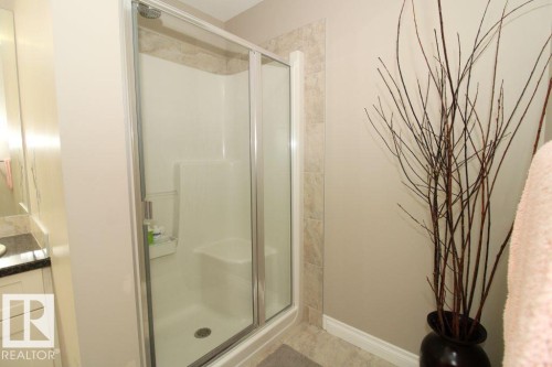 Enclosed shower with clear glass door, integrated seating, and a tiled surround - 3048 Harvey Crescent Nw, Edmonton, AB - Indoor Photo Showing Bathroom