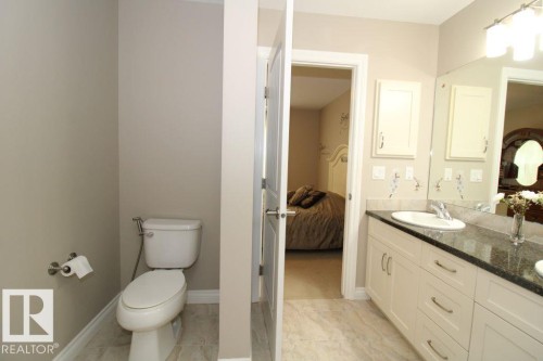 Bathroom featuring a double vanity with stone countertop, under-mount sinks, and light wood-finish cabinetry - 3048 Harvey Crescent Nw, Edmonton, AB - Indoor Photo Showing Bathroom