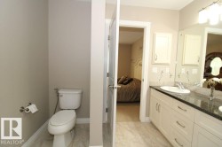 Bathroom featuring a double vanity with stone countertop, under-mount sinks, and light wood-finish cabinetry - 