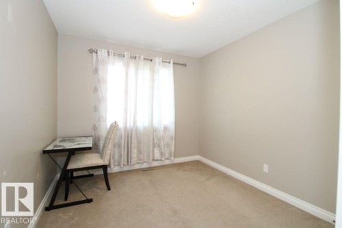Neutral-toned bedroom featuring wall-to-wall carpeting, a window with curtain rod and sheer white drapes, baseboard trim, and a ceiling-mounted light fixture - 3048 Harvey Crescent Nw, Edmonton, AB - Indoor Photo Showing Other Room