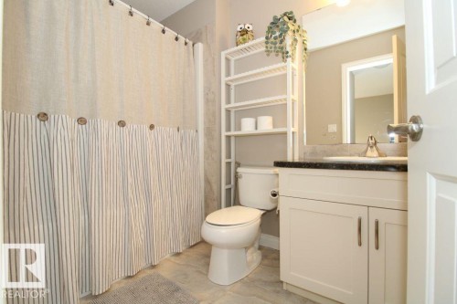 Bathroom featuring a single vanity with dark countertop, undermount sink, and chrome faucet - 3048 Harvey Crescent Nw, Edmonton, AB - Indoor Photo Showing Bathroom