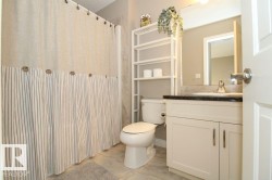 Bathroom featuring a single vanity with dark countertop, undermount sink, and chrome faucet - 
